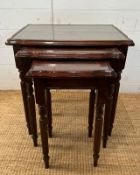 A nest of three glass top side tables with string inlay on fluted legs