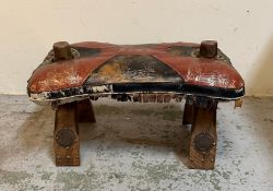 A vintage camel seat with red and black leather upholstery and an oasis pattern