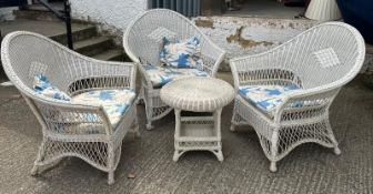 A white wicker rattan conservatory set consisting of three arm chairs and a circular table