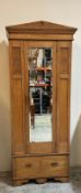 A vintage pine Arts and Crafts style wardrobe with single mirrored door opening to cross rail