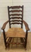A vintage Elm ladder back rocking chair with rush seat