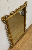 A wooden framed gold painted over mantel mirror in the Rocco style 78cm x 109cm