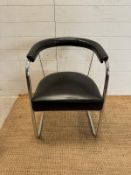 A tubular chrome Bauhaus style chair in a faux black leather upholstery