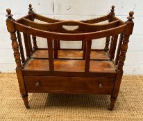 A mahogany single drawer canterbury on turned supports and castors with turned finials to top