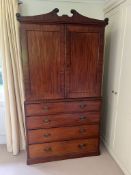 A Regency mahogany linen cupboard with panelled doors opening to fixed shelves sat upon a base