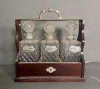 A mahogany tantalus with three cut glass decanters