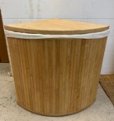 A wooden corner laundry basket with white linen interior