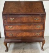 A walnut veneer three drawer bureau, the fall opening to pigeon holes and single central drawer (
