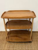An Ercol Windsor light elm three tier trolly with lipped edges (76cm x 66cm x 42cm)