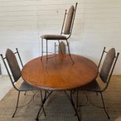 A wrought iron circular dining table and chairs, the table with a wooden top and the chairs