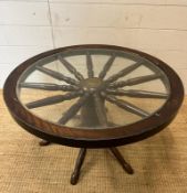 A vintage glass topped wagon wheel coffee table (H41cm Dia75cm)