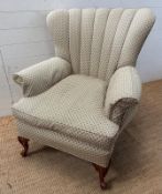 A wingback arm chair upholstered in green on carved front legs