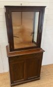 A glazed display unit upon a cabinet base with panelled doors (H174cm W81cm D50cm)