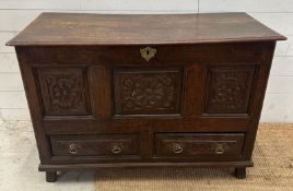 A dark oak mule chest with carved panels and drawers, hinged lid opening to storage with two drawers