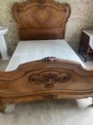 A French Louis style bedframe with a carved scrolling bed head
