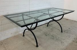 A black wrought iron garden table with glass top (H76cm W220cm D100cm)