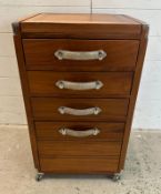 A three drawer campaign style side cabinet with hinged top opening to storage with grey suede