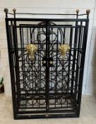A wrought iron 36 bottle wine cage with lion heads to front (H112cm W78cm D41cm)