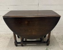 An oval oak gateleg dining table (H76cm W150cm D107cm)