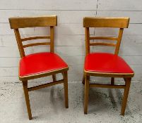 A pair of Mid Century dining chairs with red faux leather seats