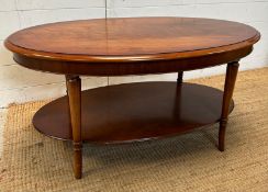 An oval coffee table with shelf under