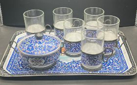 An enamel tea set to include tray, six glass cups with holders a s sugar bowl