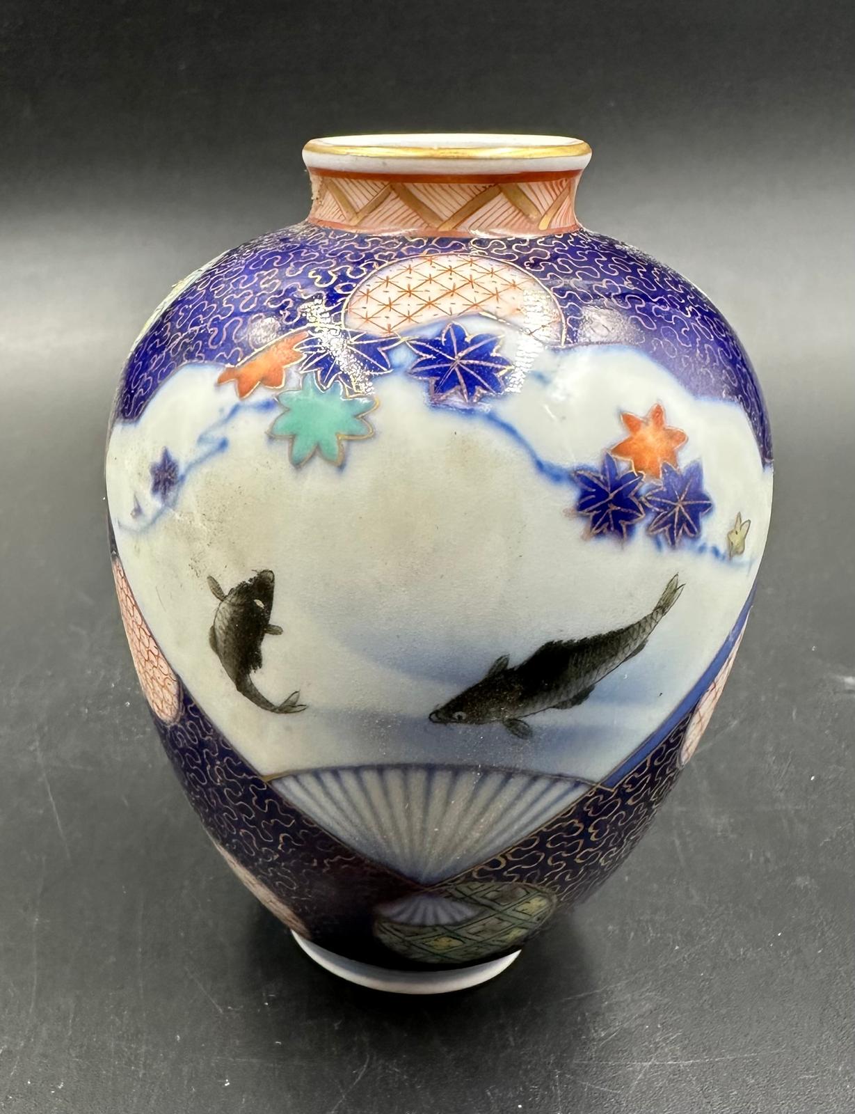 A small Japanese vase in baluster form. Blue grounds and decorated with flowers and fish Height