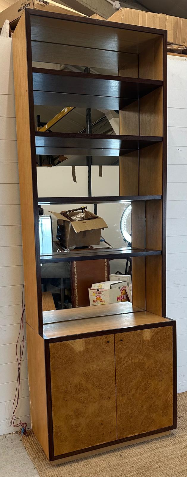 A contemporary mirror backed bookcase with four shelves and a two door cupboard under (H244 W85cm