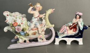 Two German fine porcelain figures of a cherub on a sleigh and a reclining lady playing an instrument