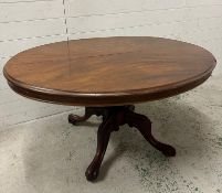 A mahogany oval tilt top centre table on turned central column with four acanthus scrolled down