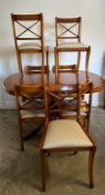 A Bradley veneered extendable pedestal dining table on brass lions paw feet and seven chairs (