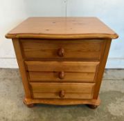 A pine three drawer bedside table on bun feet (H52cm W53cm D40cm)