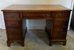 A brown leather topped pedestal desk, central long drawer flanked by four shorter (H76cm W120cm