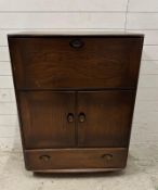 A dark Ercol bureau on castors, the fall opening to writing surface and storage with a two door