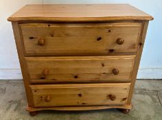 A pine three drawer chest of drawers on bun feet (H72cm W79cm D46cm)
