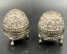 A pair of white metal pepper pots