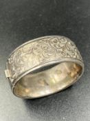 A silver hinged bangle with foliate decoration
