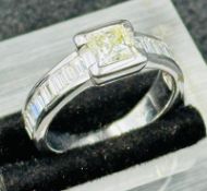 A hallmarked 18ct white gold princess and baguette cut diamond ring, consisting of a central 5.
