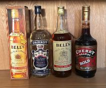 Four bottle of spirits, a Smirnoff blue label, a Bols Cherry brandy, and two bottles of Bells, a one