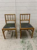 A pair of mid century kitchen chairs with green faux leather seats