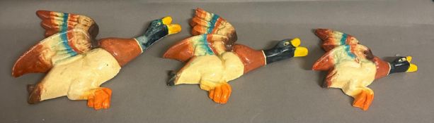 A set of three graduated wall hanging flying ducks