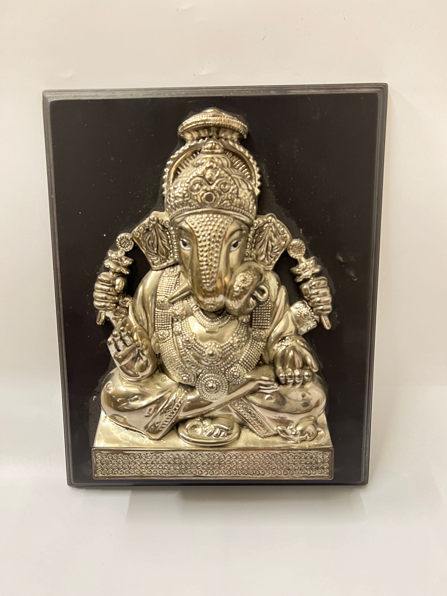A white metal Ganesha repousse sculpture on board 31cm x 25cm