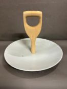 A white ceramic serving platter with a wooden shovel handle by Thorsten Van Elten