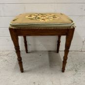 An oak framed piano stool with a florally upholstered seat