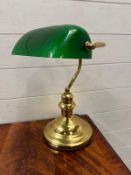 A brass bankers lamp with green shade