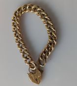 A rose gold flat curb-link bracelet with textured decoration and heart-shape locket, stamped 9ct