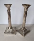 A pair of George V silver corinthian candlesticks with removable sconces, fluted columns on stepped