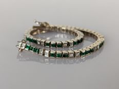 An emerald and diamond tennis or line bracelet on a white gold setting