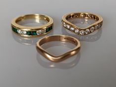 An emerald and diamond channel-set ring on a tapering shank; a wishbone diamond eternity ring