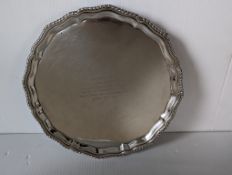 An Edwardian circular silver salver with pie crust border on three claw and ball feet, 26 cm diamete